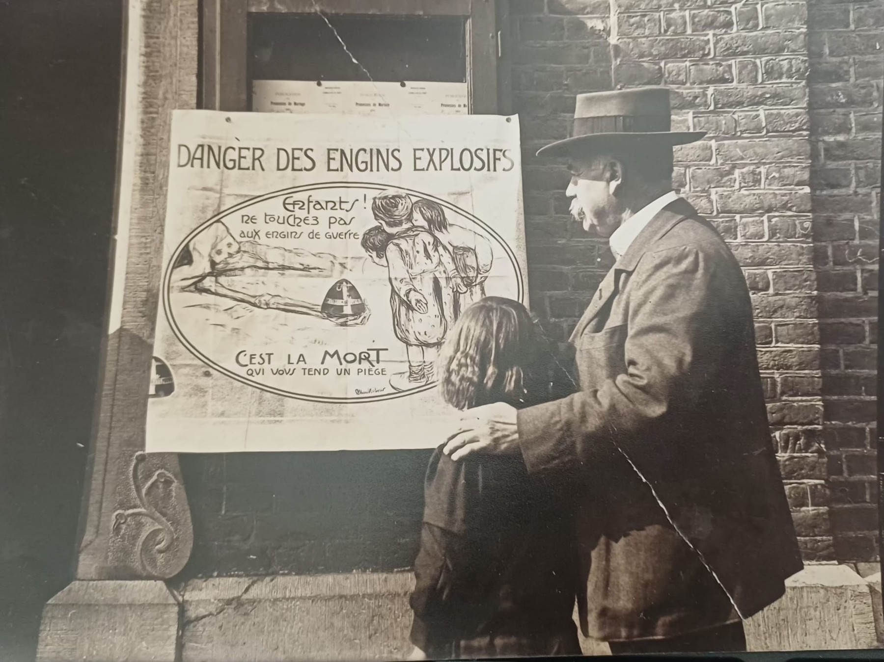 Joseph Lejeune devant une affiche de prévention sur les engins de guerre